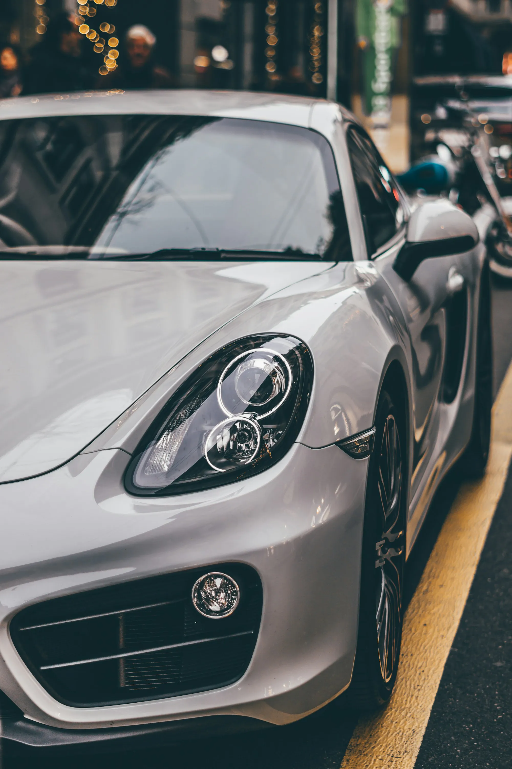 Light tracing the silver bonnet and curved headlight of a Porsche coupe.